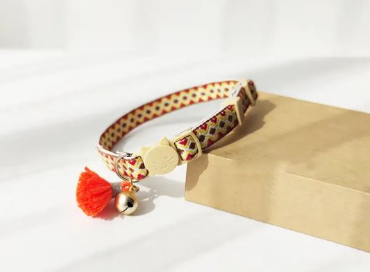 Quick Release Adjustable cat collar with beige buckle, diamond ribbon and orange tassel.